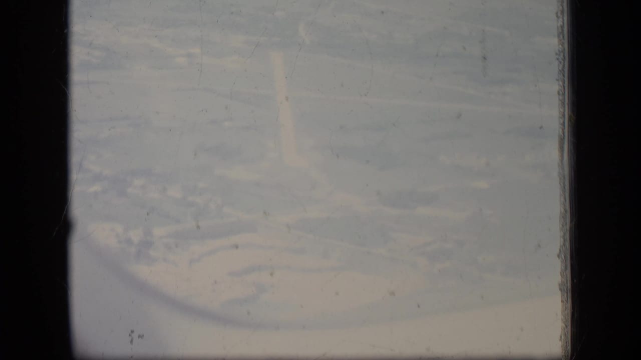 Aerial 8mm view over a New Jersey facility area in 1970, with indistinct buildings, haze, dust, and visible film wear.