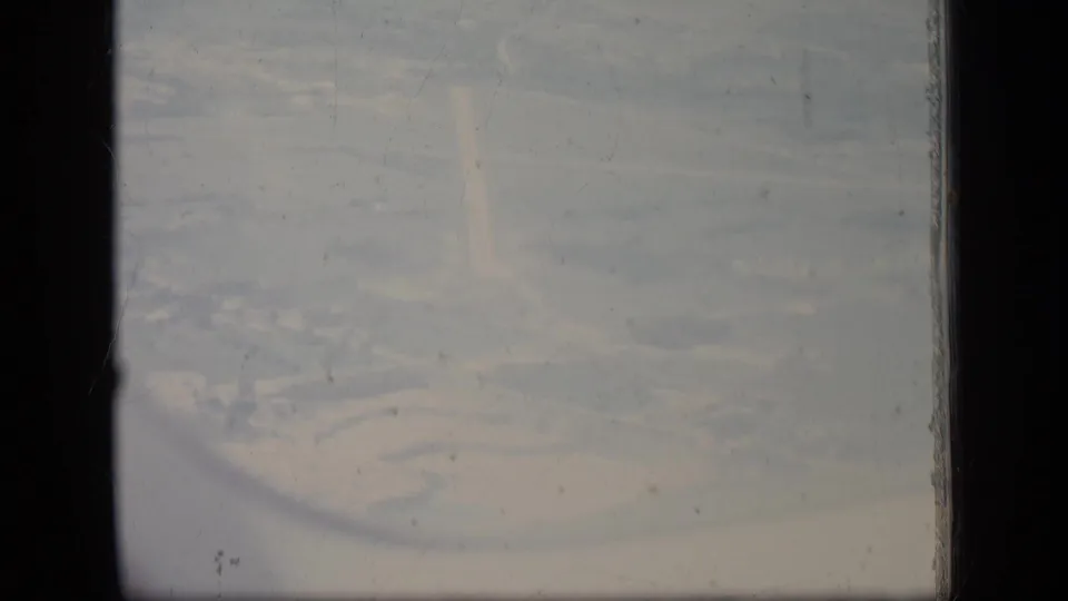 Aerial 8mm view over a New Jersey facility area in 1970, with indistinct buildings, haze, dust, and visible film wear.