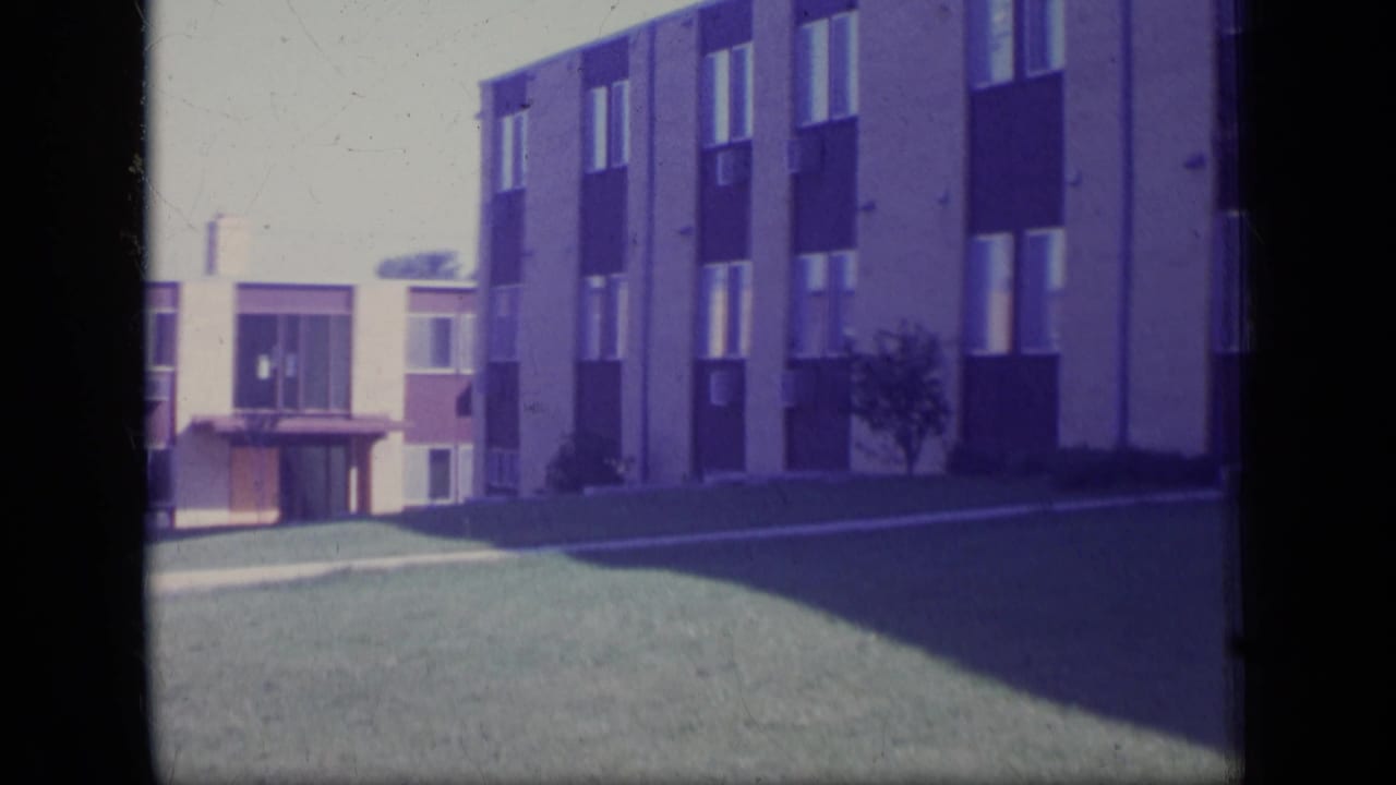 Closer view of an apartment building facade beside a lawn and walkway.