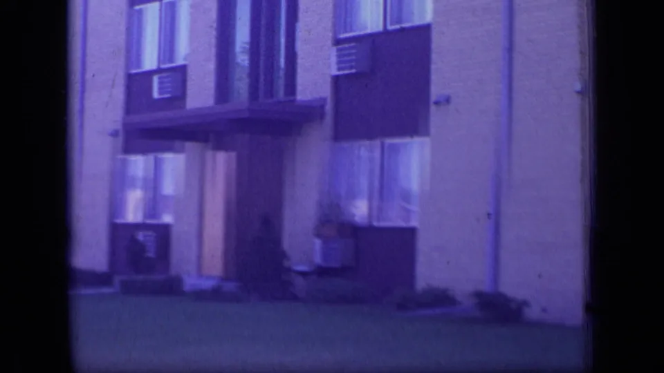1970 New Jersey frame of the apartment facade, with the entrance partly centered and windows and air conditioners visible above the lawn.