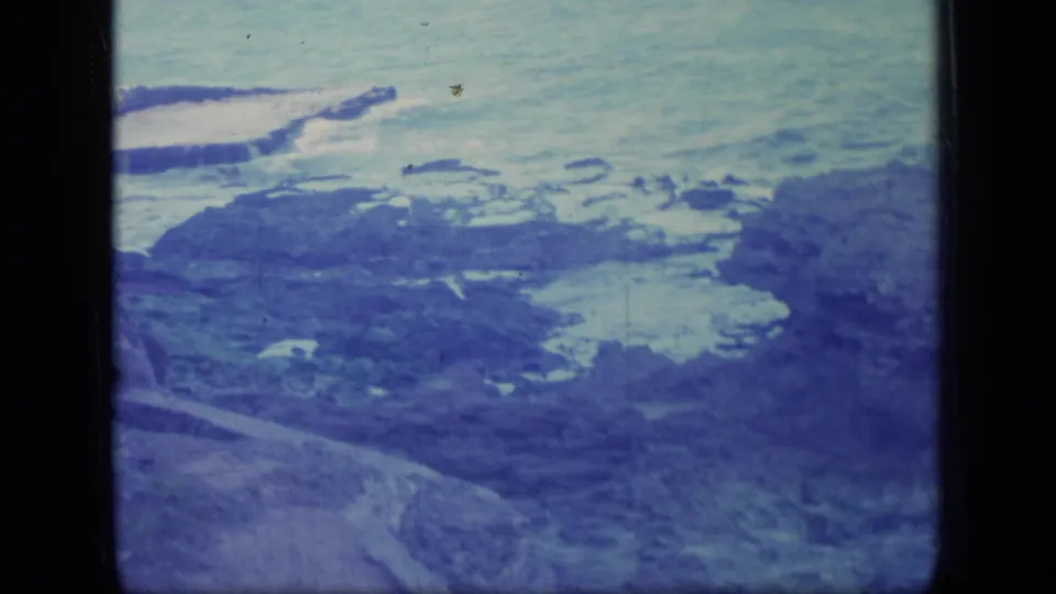 Puerto Rico rocky beach scene from 1970 home-movie footage, with surf, tide pools, and a sloping coastal foreground.