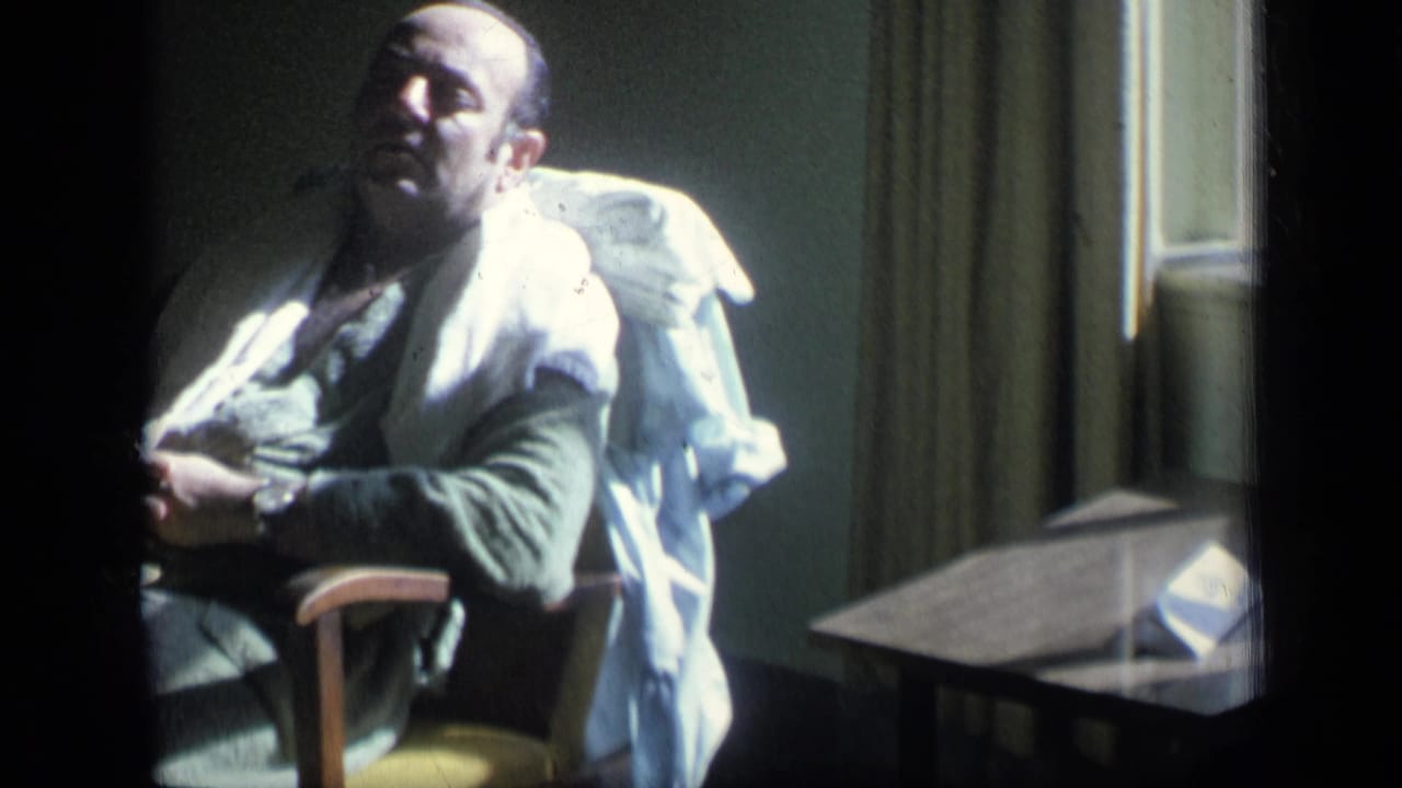 Man in a chair beside a window with a white garment draped over him.