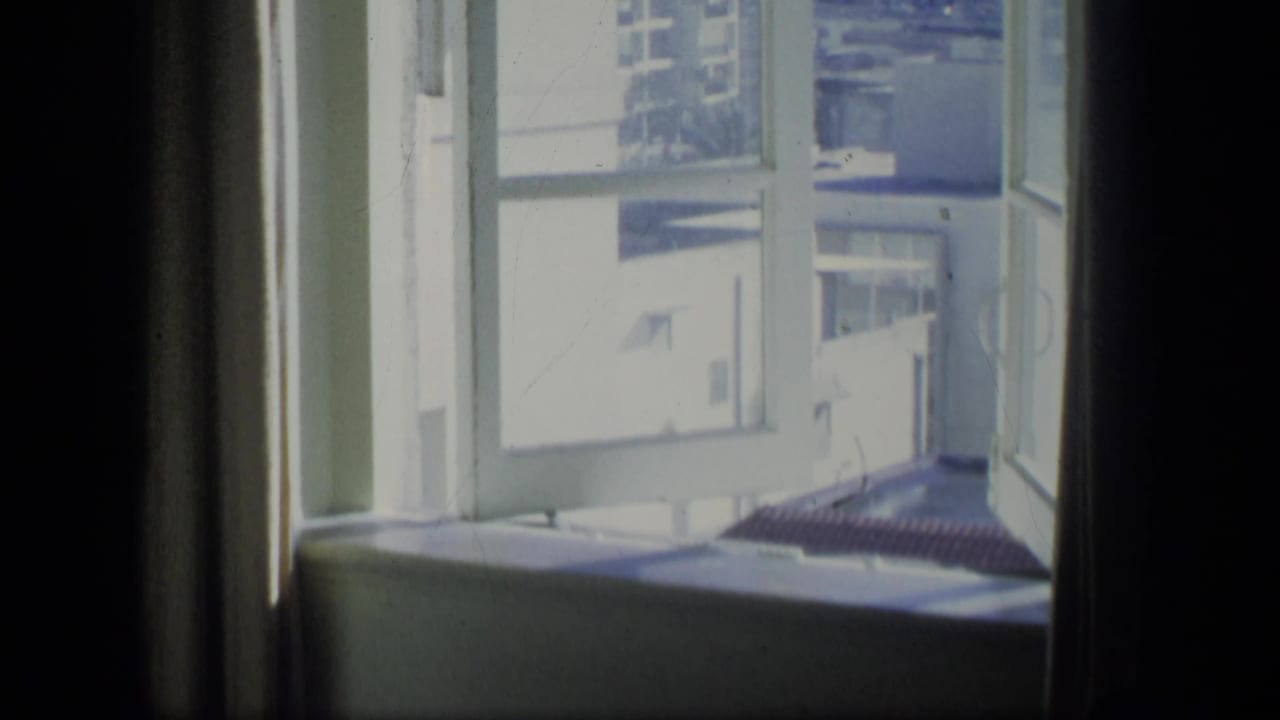1970 Puerto Rico 8mm frame looking past a window frame toward a bright street and building exterior.