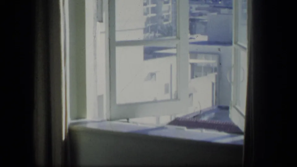 1970 Puerto Rico 8mm frame looking past a window frame toward a bright street and building exterior.