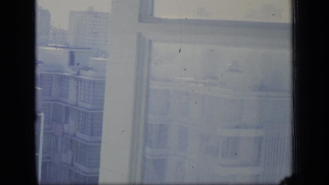 Soft, hazy view of apartment facades through window panes and a central dark divider.