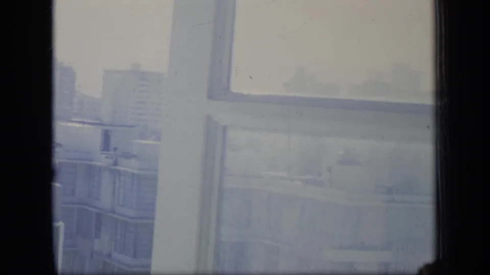 The 1970 Puerto Rico home-movie view includes a nearby apartment block, distant buildings and a bright hazy skyline through glass.