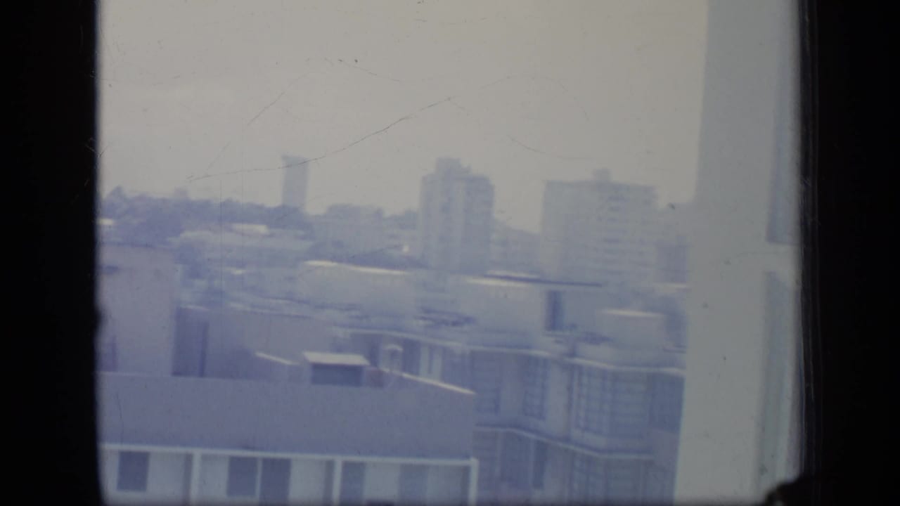 Hazy apartment buildings seen through a dark window frame.