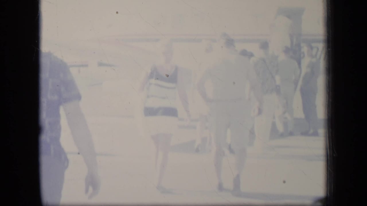 Overexposed 1970 Puerto Rico frame with passengers in vacation apparel approaching a small plane.
