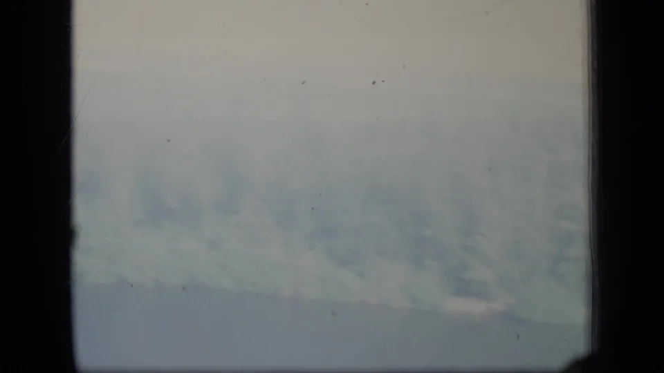 A bluish clouded view on vintage 8mm stock, bordered by heavy gate shadows and light film wear.