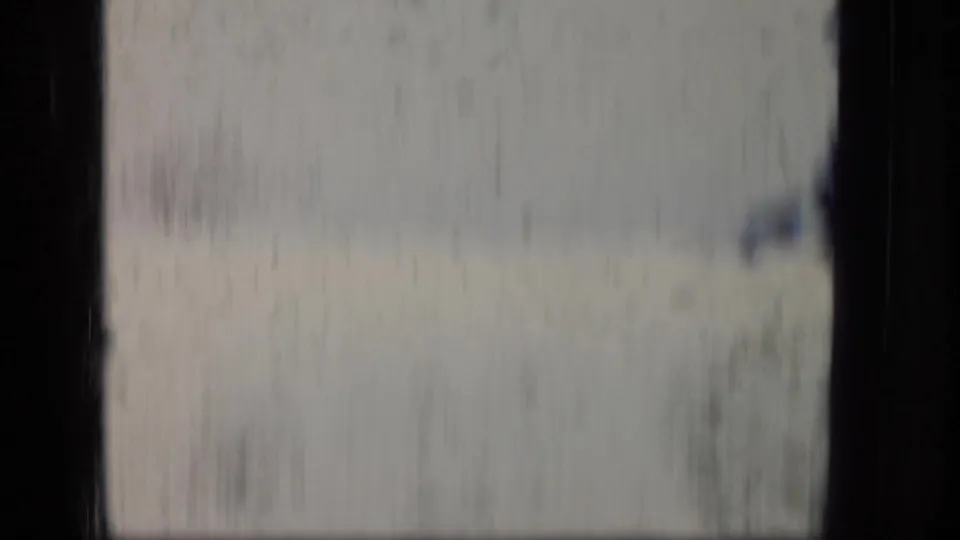1970 Puerto Rico 8mm frame showing a soft, blurred airplane-window view with dark window bars and hazy terrain outside.