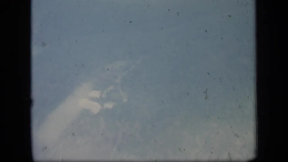 1970 Puerto Rico 8mm frame with a soft aerial view of hazy terrain and possible coastline or water through the aircraft window.