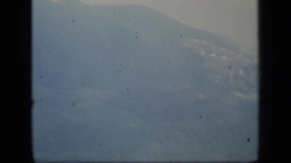 1970 Puerto Rico frame showing a broad hazy mountain slope, pale sky, black gate border, and small film marks.
