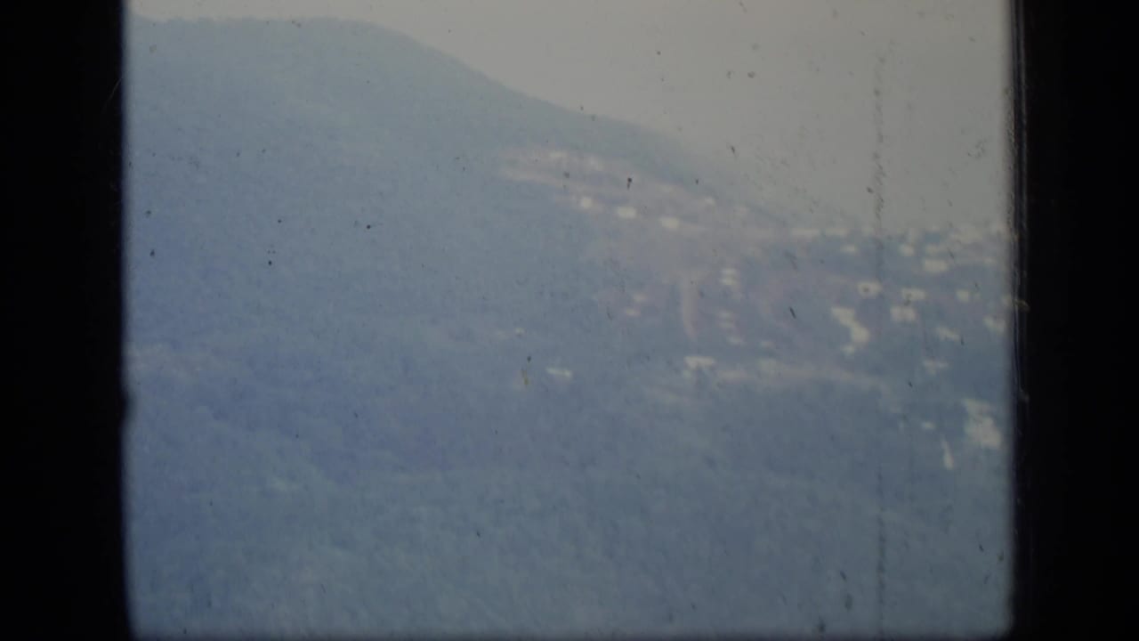 Hazy mountain ridge seen through dark airplane window framing.