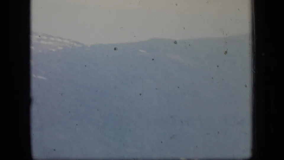 Soft, hazy Puerto Rico mountain terrain from a 1970 airplane-window home movie, with faint ridge lines and a few light patches.