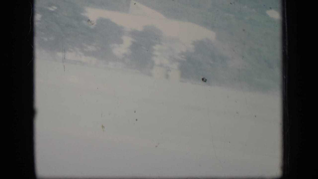 Faded 8mm frame from the Puerto Rico clip showing a bright exterior view with faint trees before the airplane arrival shot.