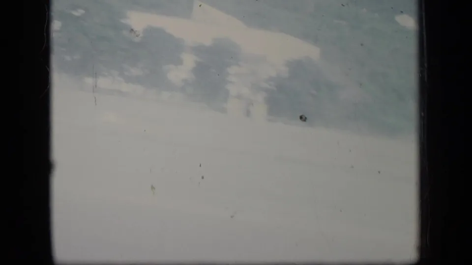 Faded 8mm frame from the Puerto Rico clip showing a bright exterior view with faint trees before the airplane arrival shot.