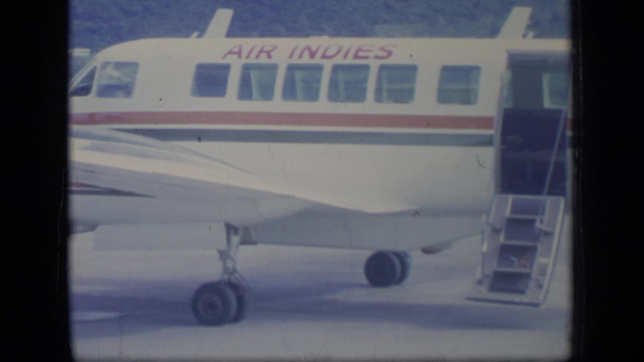 Air Indies aircraft side with open door, boarding stairs and landing gear visible.