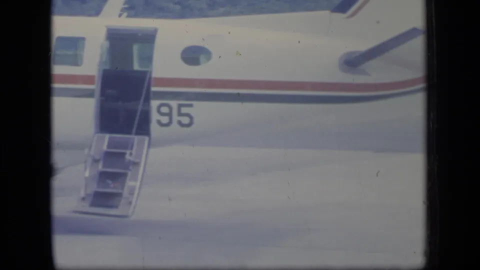 Closer 8mm view of the Air Indies fuselage in Puerto Rico, centered on the open door, boarding stairs, round window and number 95.