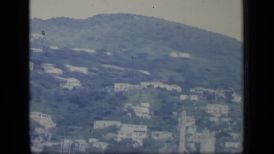 Puerto Rico hillside settlement filmed from the air, with white buildings spread across green slopes on 8mm film.