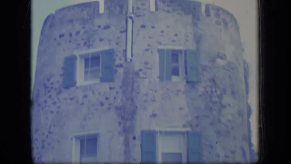 1970 Puerto Rico frame showing the upper facade of a stone building, with shuttered windows and mottled masonry texture.