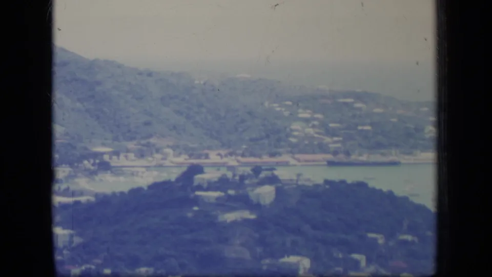1970 Puerto Rico home-movie view of foothills, scattered buildings, roads, and a possible coastal waterline beyond the valley.