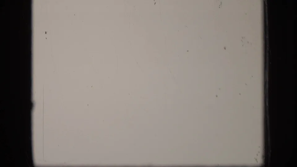 A mostly blank 8mm frame shows faint scratches, dust and the edge of the film gate.