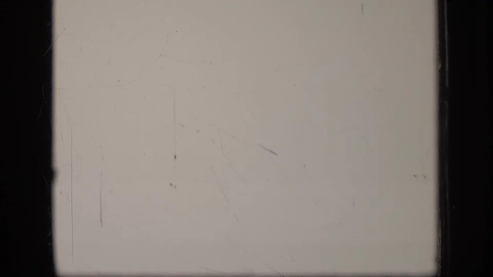 A pale blank 8mm frame with vertical gate edges, dust specks and light scratching.