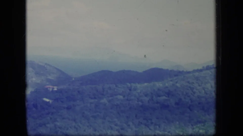 1970 Puerto Rico home-movie frame of rolling wooded hills, pale sky, and blue-tinted 8mm exposure.