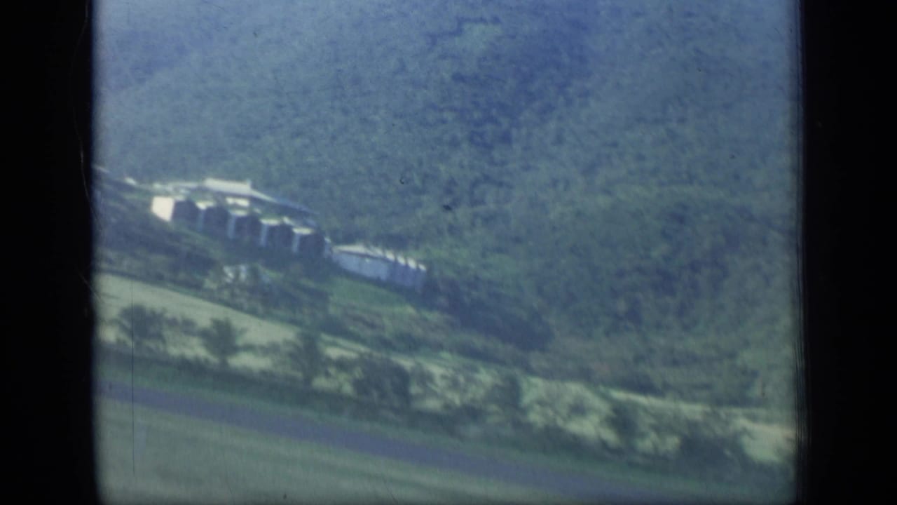Hillside buildings and green fields seen from the air.