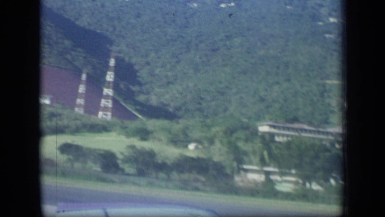 Distant red-roofed building on a green hillside near the coast.