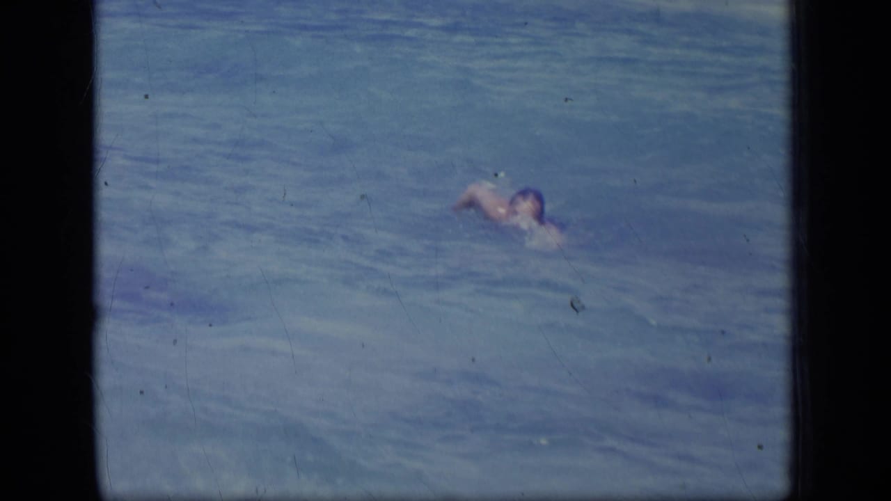 A man swims across rippled ocean water in metadata-supported 1970 Puerto Rico home-movie footage.