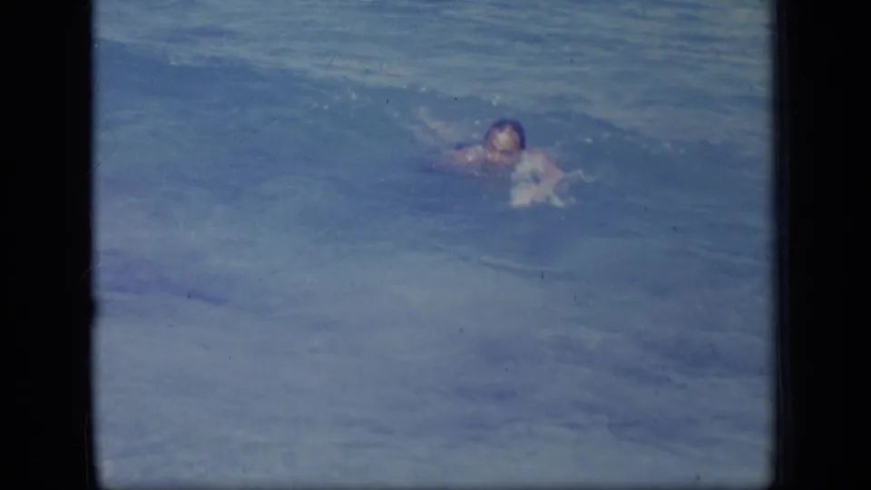 The swimmer faces toward the camera while moving through blue ocean water in a faded 8mm Puerto Rico scene from 1970.