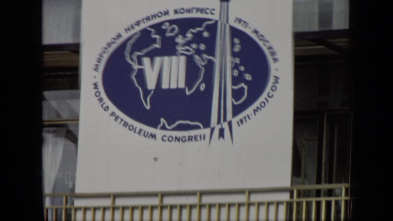 Congress banner with blue oval logo and text, seen beside building windows and dark foreground framing.