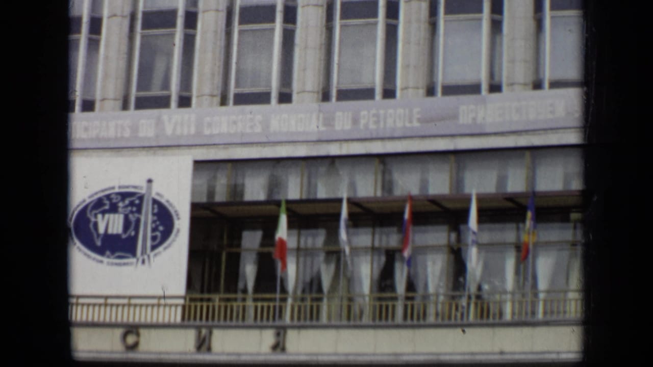 Conference building facade with VIII emblem, banner text, and flags on a balcony.