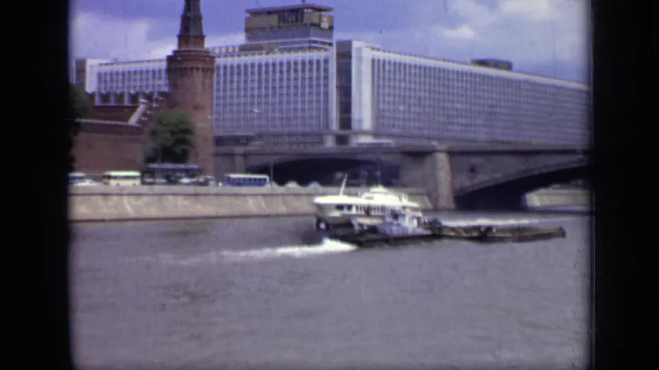 A white hydrofoil skims the Moscow river while a tug and barge pass near the embankment below Hotel Ukraina.