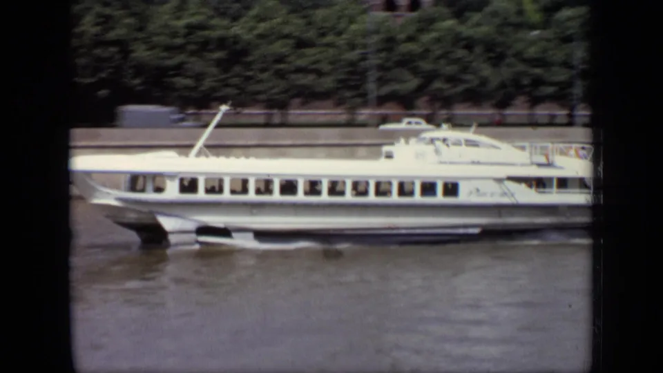 1971 Moscow 8mm frame with a closer side view of the white hydrofoil, its windows, hull, wake, and blurred riverbank trees behind it.
