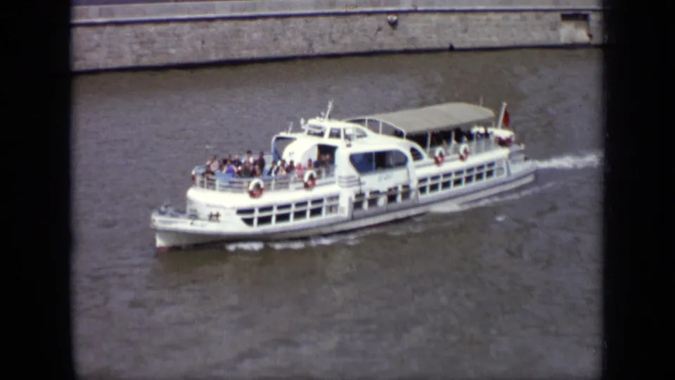 1971 Moscow 8mm frame of a white passenger boat crossing the river, with people visible on the open deck.