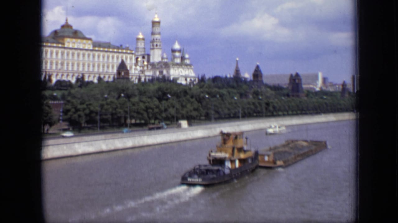 1971 Moscow view of river traffic passing beneath a skyline of Kremlin-area towers, trees, and embankment walls.