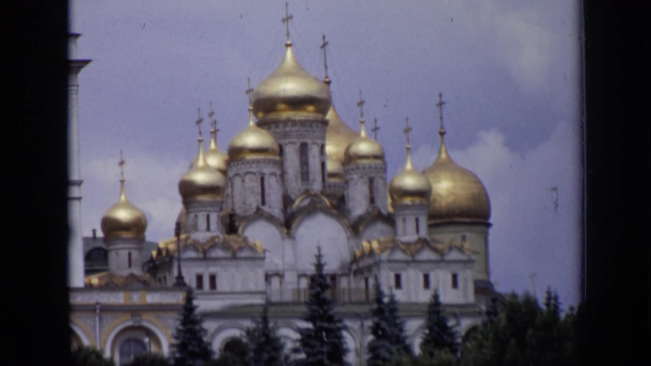 White cathedral facade with multiple golden domes seen through a dark vertical edge.