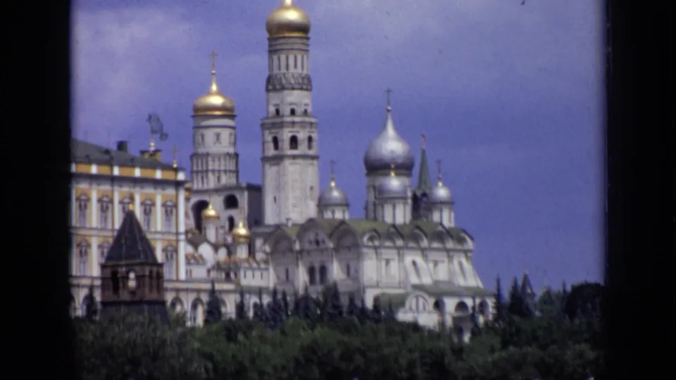 Final 1971 Moscow 8mm frame showing Kremlin domes and a bell tower behind trees, with palace architecture at the left edge.