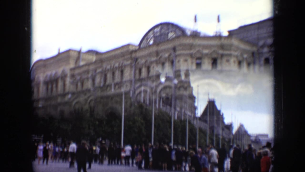 Visitors gathered along a wide plaza beside a large historic building.
