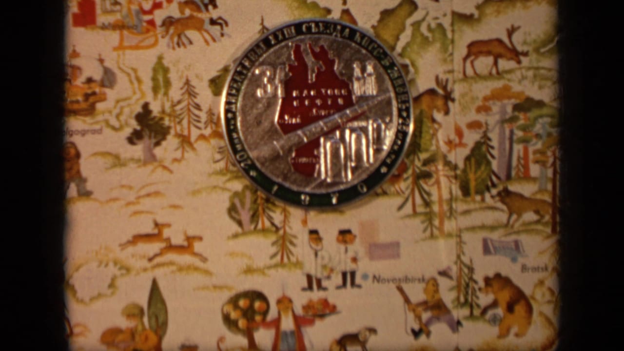 Cyrillic commemorative coin centered on a patterned cloth with drawn animals and landscape details.