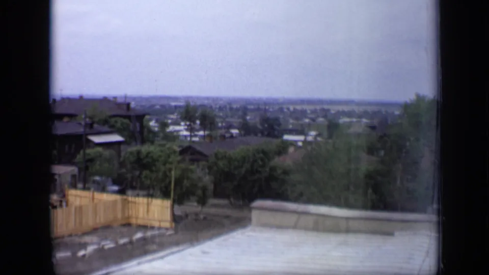 1971 Moscow residential panorama with a pale roof edge, leafy trees, small buildings and a soft distant skyline under overcast light.