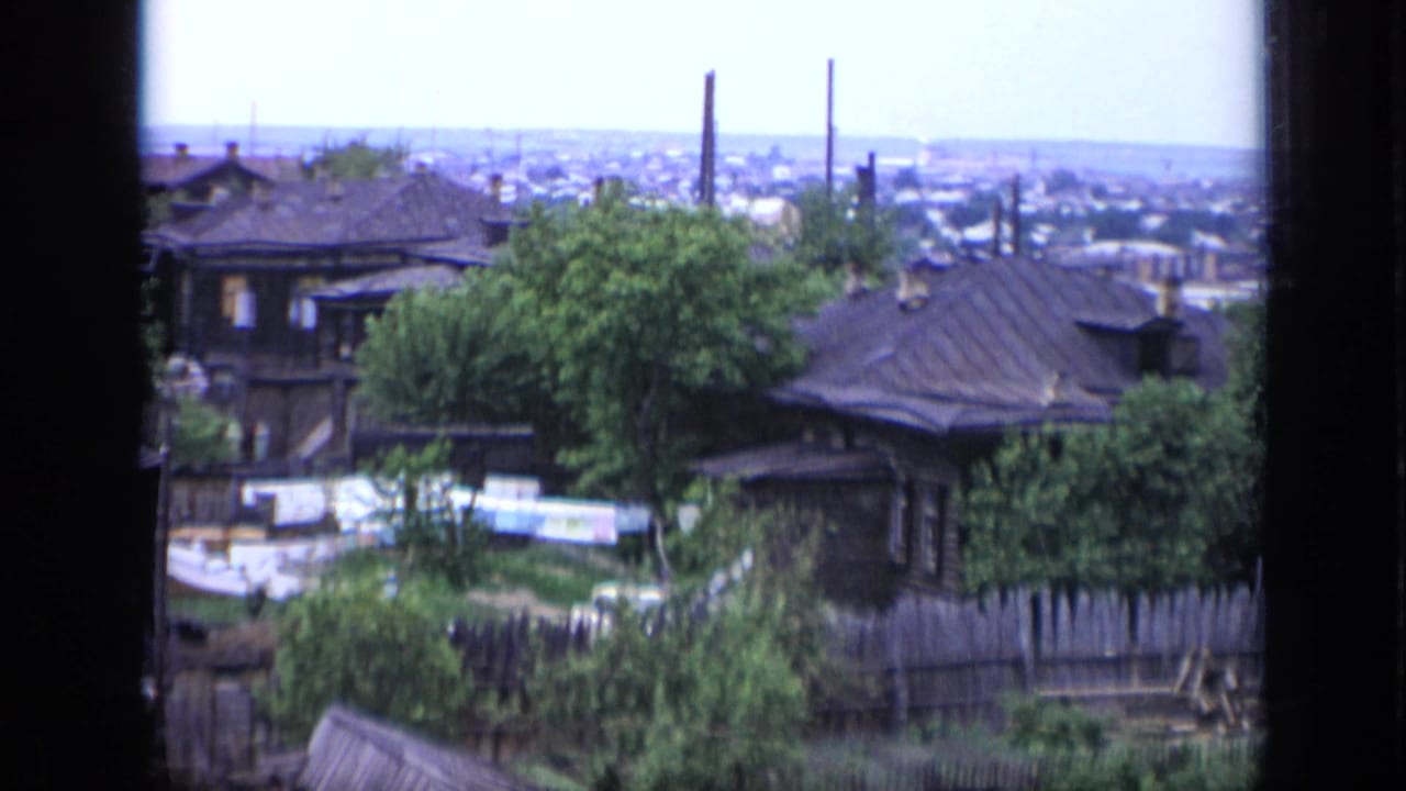 1971 Moscow 8mm frame looking over rooftops, fences, trees, and a distant urban horizon before the helicopter scene.