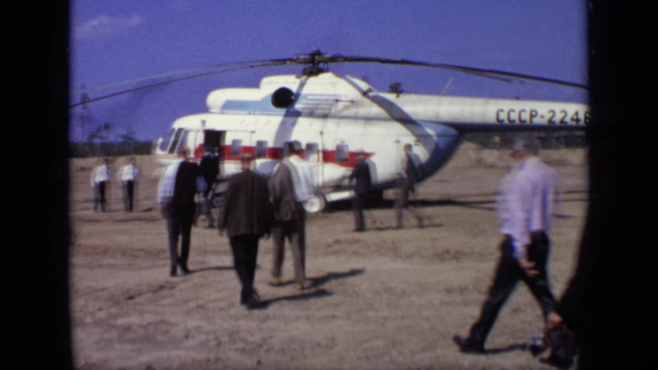 A group of men walk near the side of a white helicopter marked CCCP-22462.