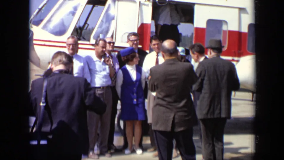 Near the helicopter door, suited men and a woman in a blue uniform stand together in the 1971 Moscow footage.