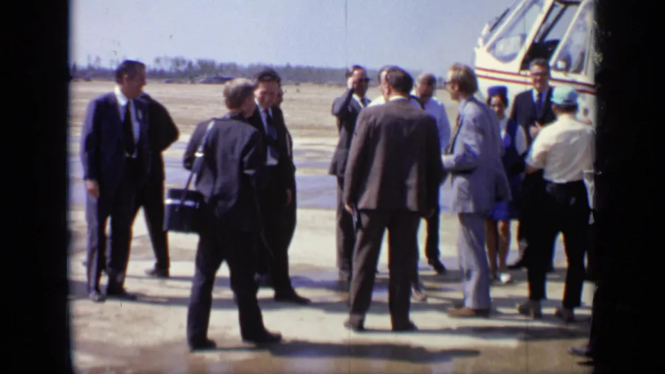 Adults in formal clothing stand and converse near the helicopter during a 1971 Moscow airfield arrival.