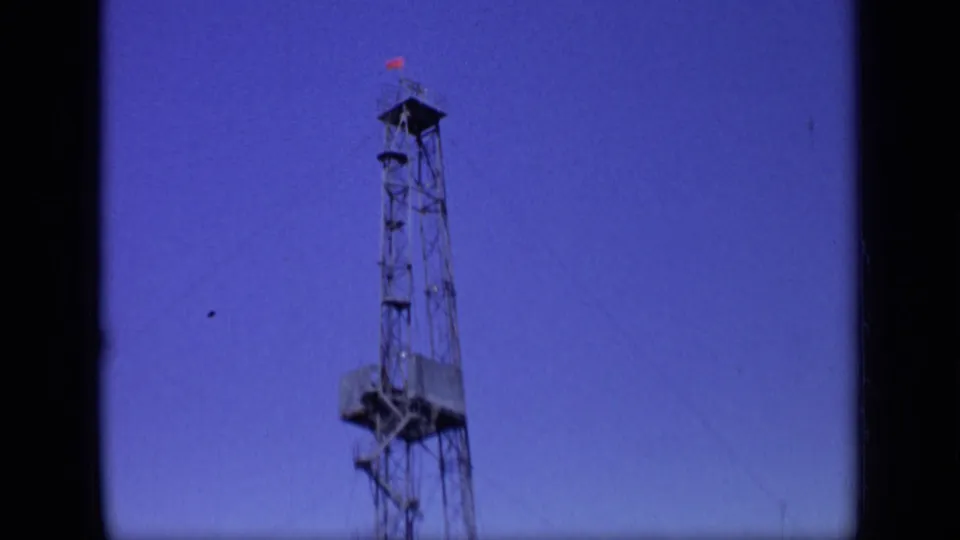 1971 Moscow 8mm frame showing a tall lattice drilling rig with a small red flag against a saturated blue-purple sky.