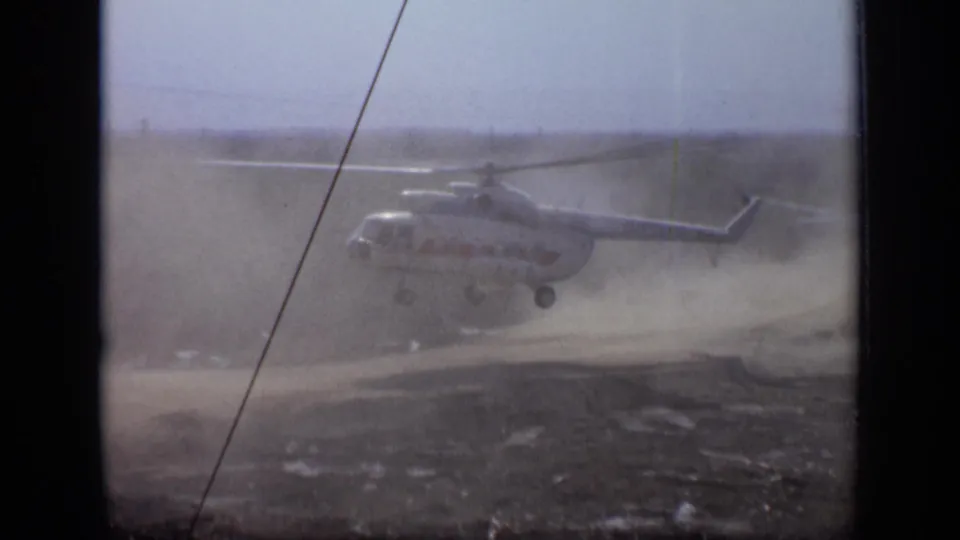 1971 Moscow-area home-movie frame with the helicopter airborne and partially veiled by dust from the landing zone.