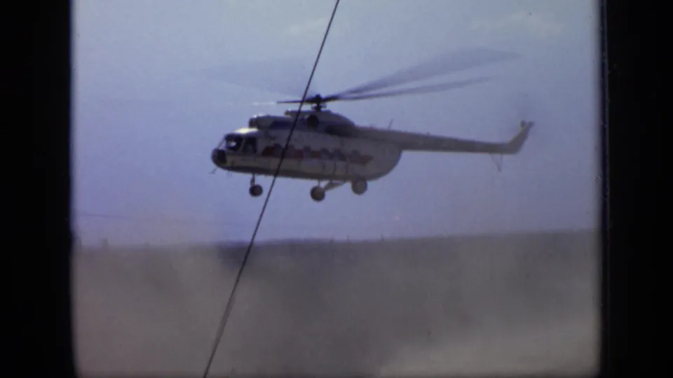 1971 Moscow 8mm frame showing the helicopter airborne above a dusty field, with landing gear down and soft faded color.